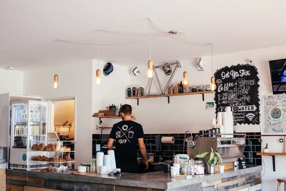 A barista preparing drinks behind a café counter.